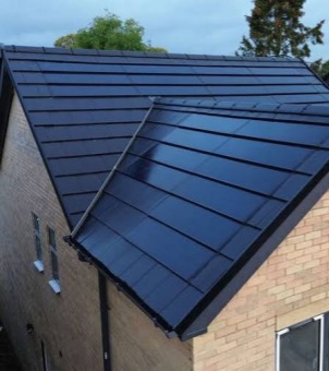 Close-up of a brick house with a pitched roof fitted with GreenMore solar tiles.